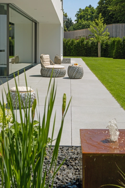 Terrasse mit großen Terrassenplatten in Grau vor einer Fensterfront