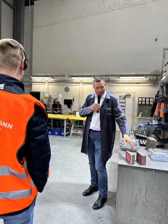 Werksführung: Guide erklärt einen Sachverhalt in einer Produktionshalle.