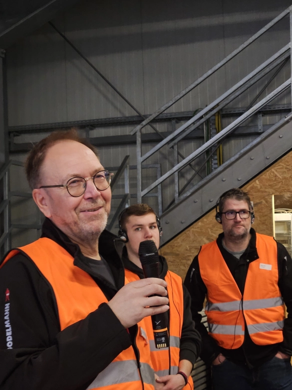 Werksführung: Guide erklärt einen Sachverhalt in einer Produktionshalle.