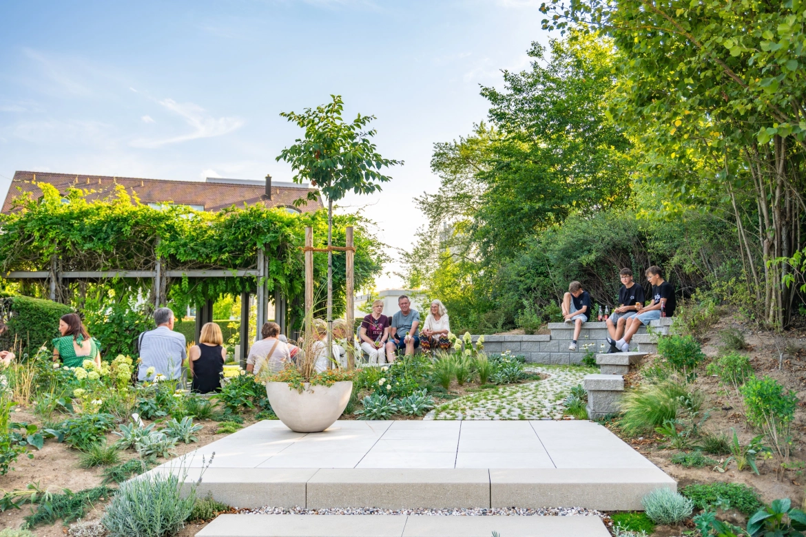 Die Besucher des Konzerts sitzen in Grüppchen verteilt im GODELMANN Ideen-Garten, zwischen üppigem Grün und unterschiedlichen Musterflächen.