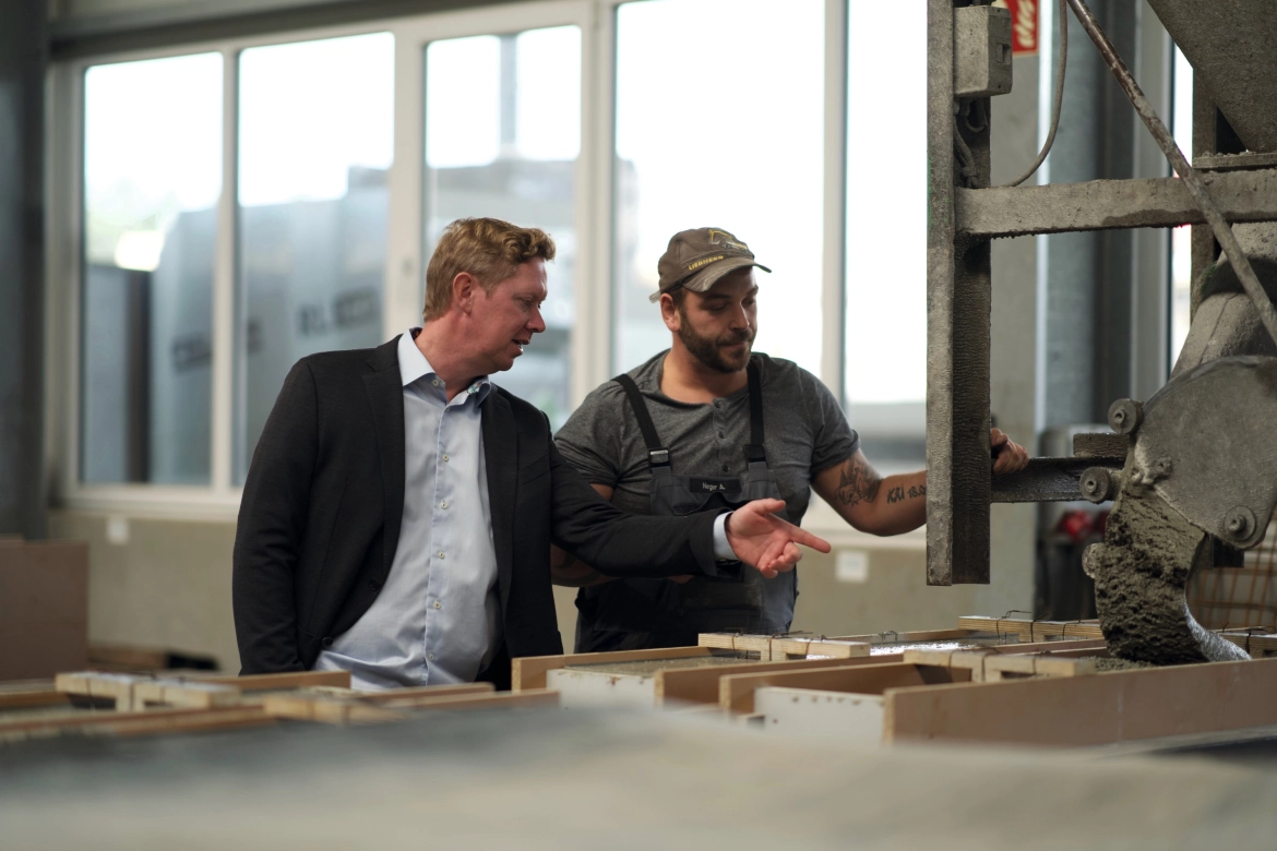 Two people stand in the concrete manufactory in front of formwork for special concrete components. They are discussing the formwork.