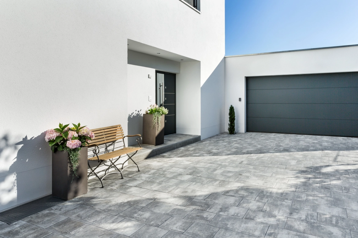 Driveway to a white detached house with gray-black nuanced paving