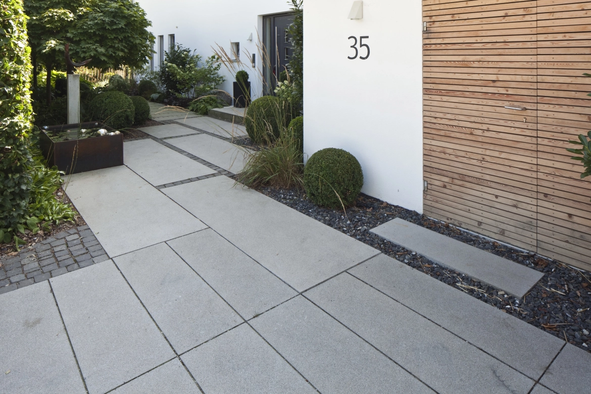 elongated paving stones to a modern house with a wooden door as a garage and bicycle gate
