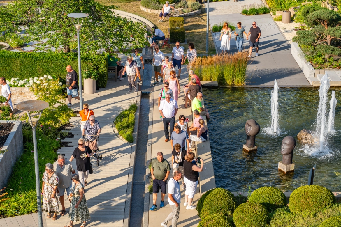 GODELMANN Ideen-Garten: Die Besucher des Konzerts schlendern durch den grün angelegten Garten, vorbei an einem Wasserbecken.