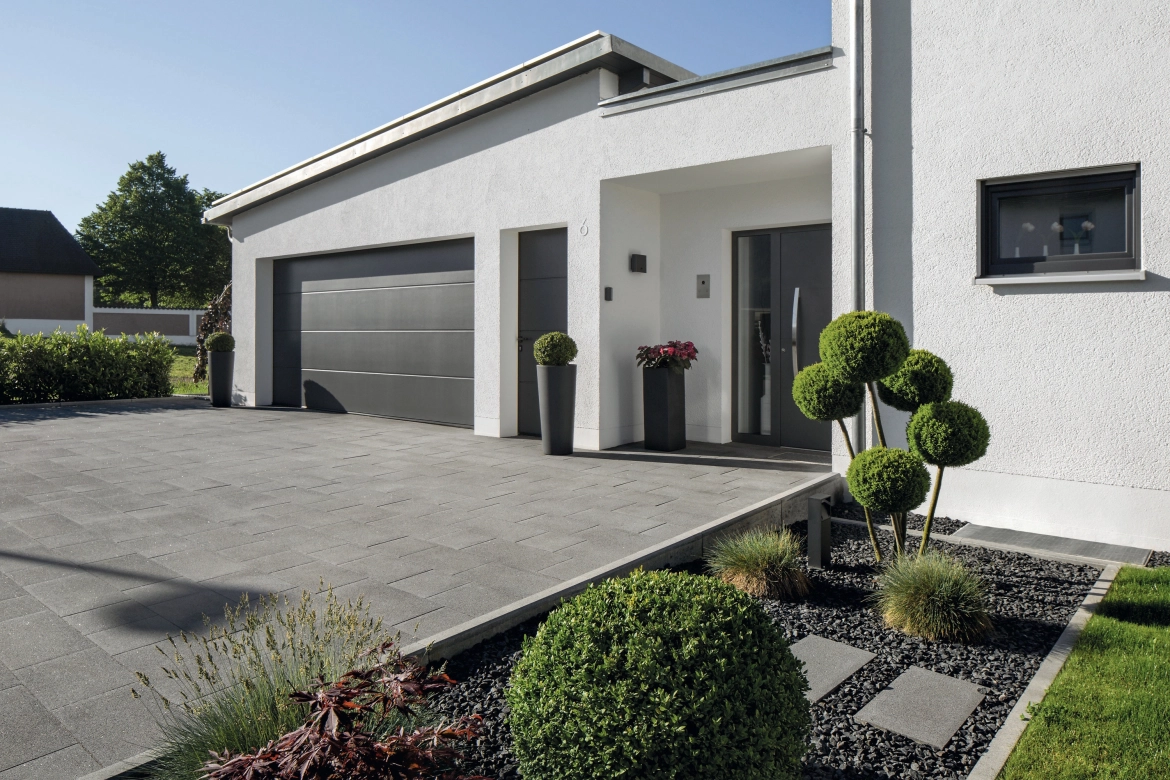 Driveway with garage to a modern house with dark paving