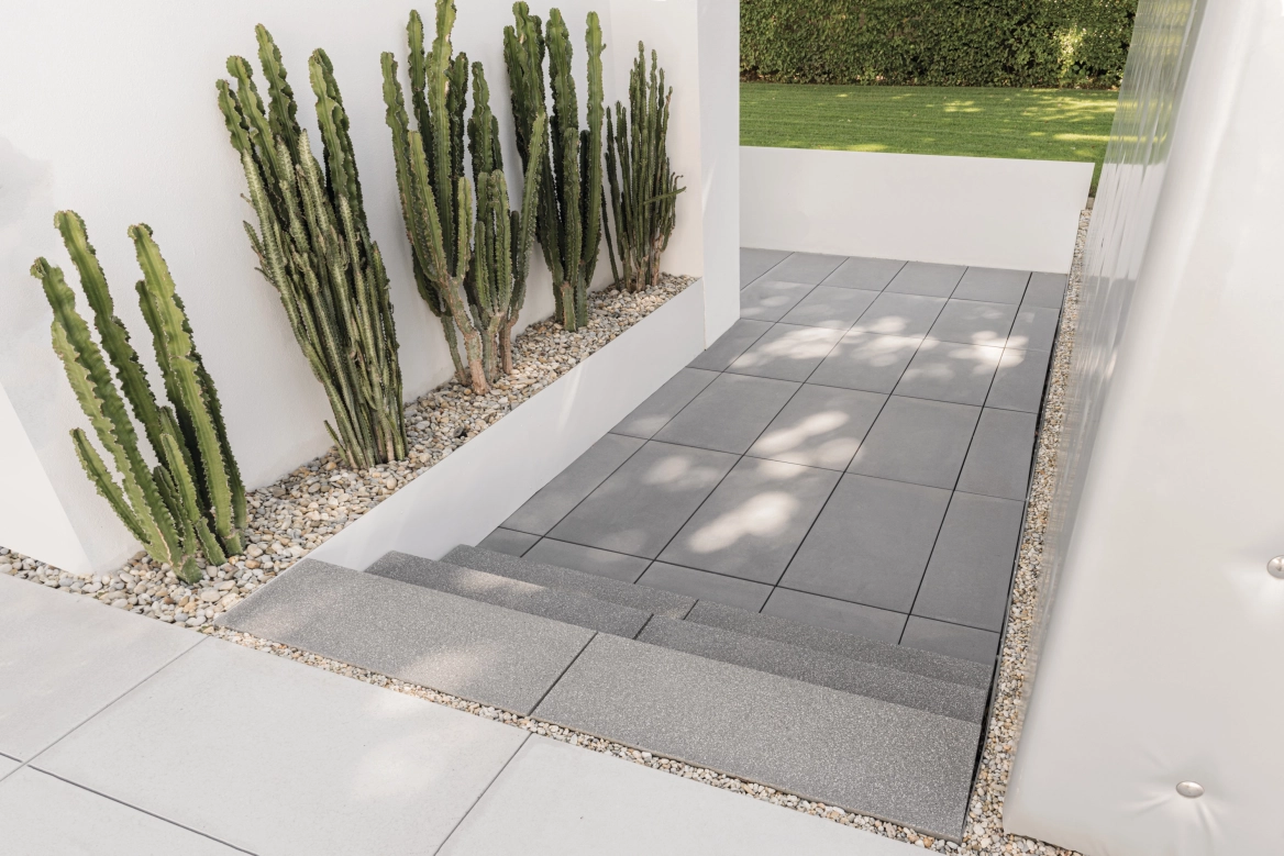 Paving steps made of exposed concrete as a walkway in a private house with cacti as decoration.