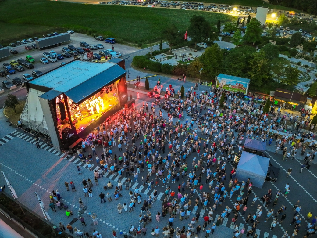 Luftbild am Abend von der Open-Air Fläche während des Konzerts auf dem das Konzert stattgefunden hat: Der GODELMANN LKW Parkplatz und der GODELMANN Ideen-Garten sind zu sehen sowie mehrere Tausend Menschen vor der Bühne.