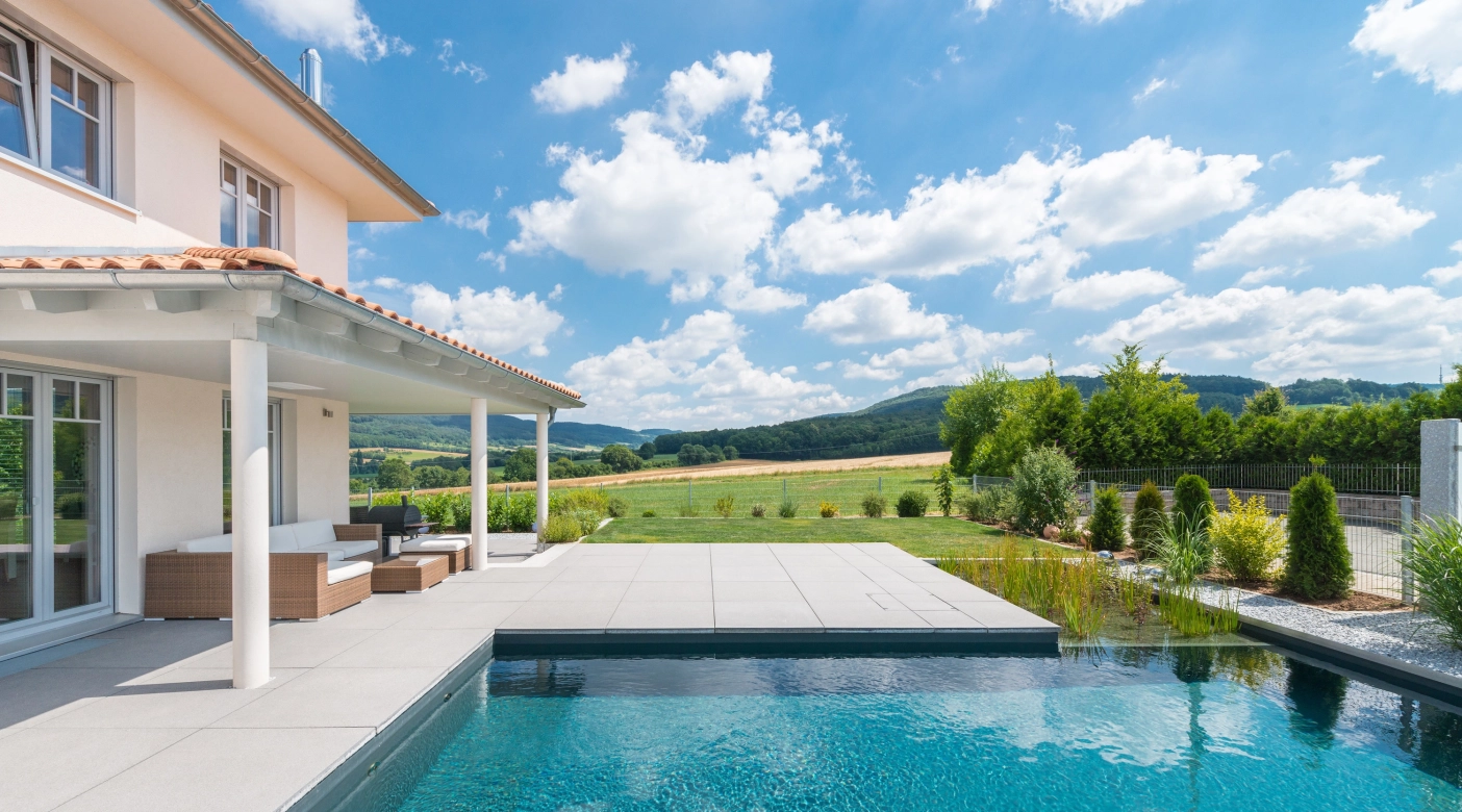 Haus im Grünen mit angelegten Pool und natürlichen Filter umgeben von einer schönen  Terrassen mit großen Terrassenplatten