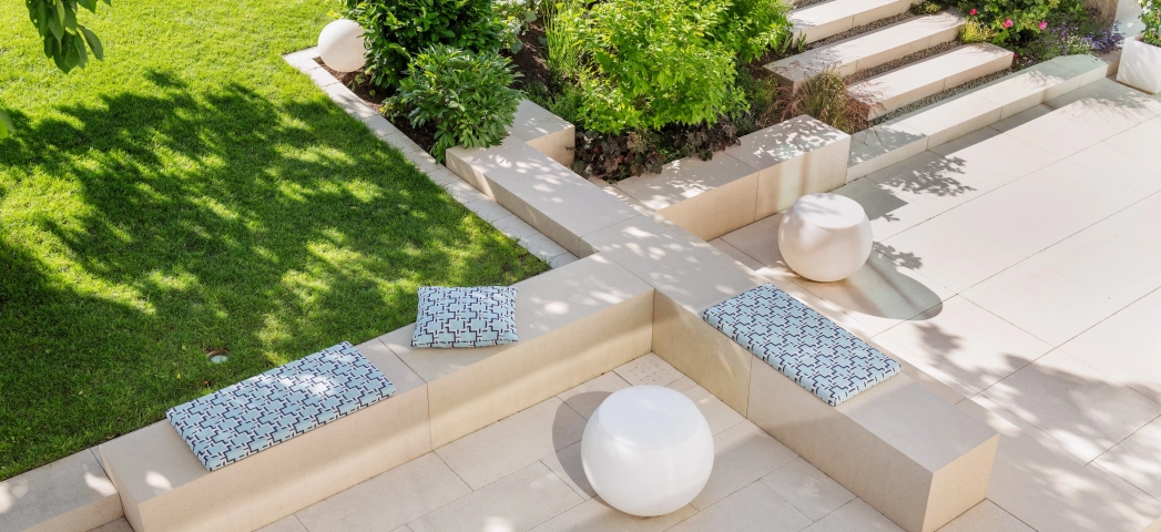 Private modern garden with sandstone-colored terrace and lots of greenery