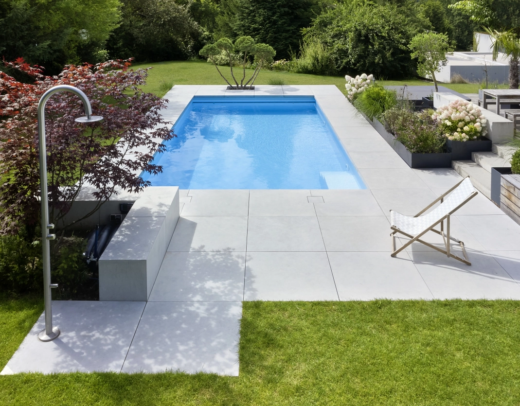 Pool mit großen Terrassenplatten GDM.Massimo in grau, Außendusche, Sträuchern und andere diverse Pflanzen