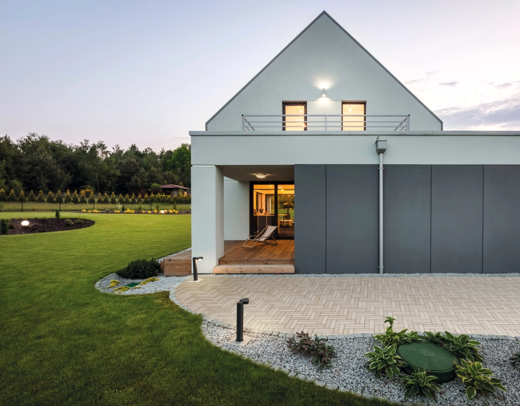 Haus mit grünem Garten und Terrasse mit Pflasterstein GDM.Liva stone in Farben Kalkstein hell, mittel und dunkel im Kleinformat verlegt in Fischgrätmuster