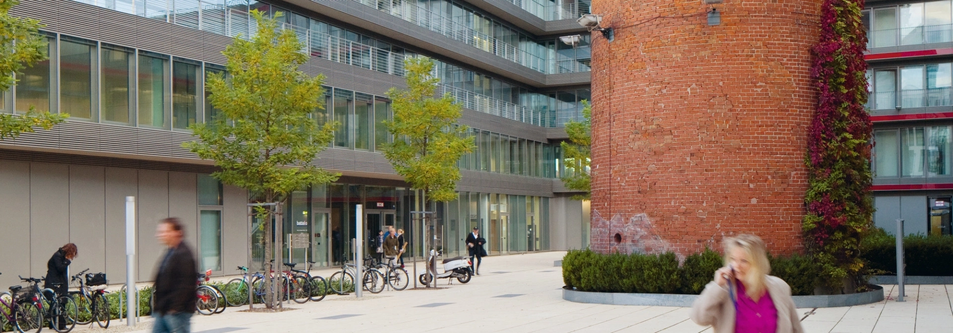 Großer Ziegelturm auf großflächigem Innenhof eines gläsernen Gebäudekomplexes