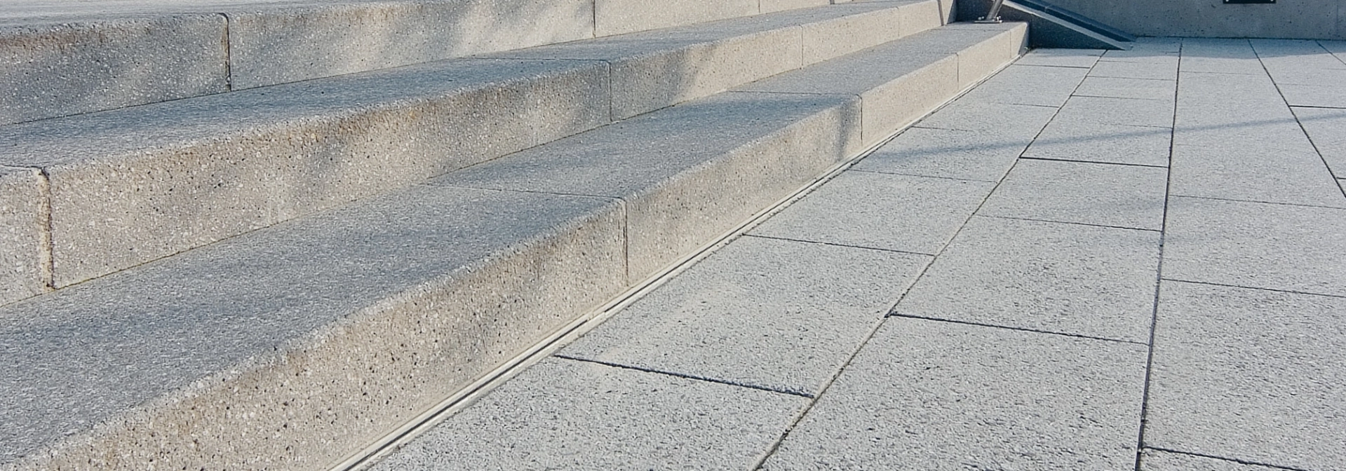 hellgrau gepflasterte Treppenanlage zum Eingang des Thermalbades mit Bäumen