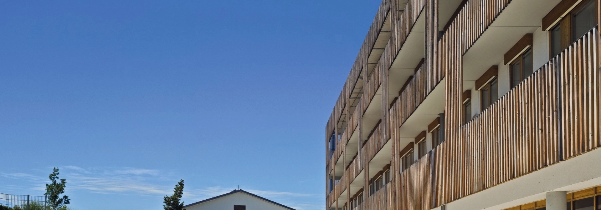 Realschulgebäude mit Holzfassade und Vorplatz mit modernem Pflaster