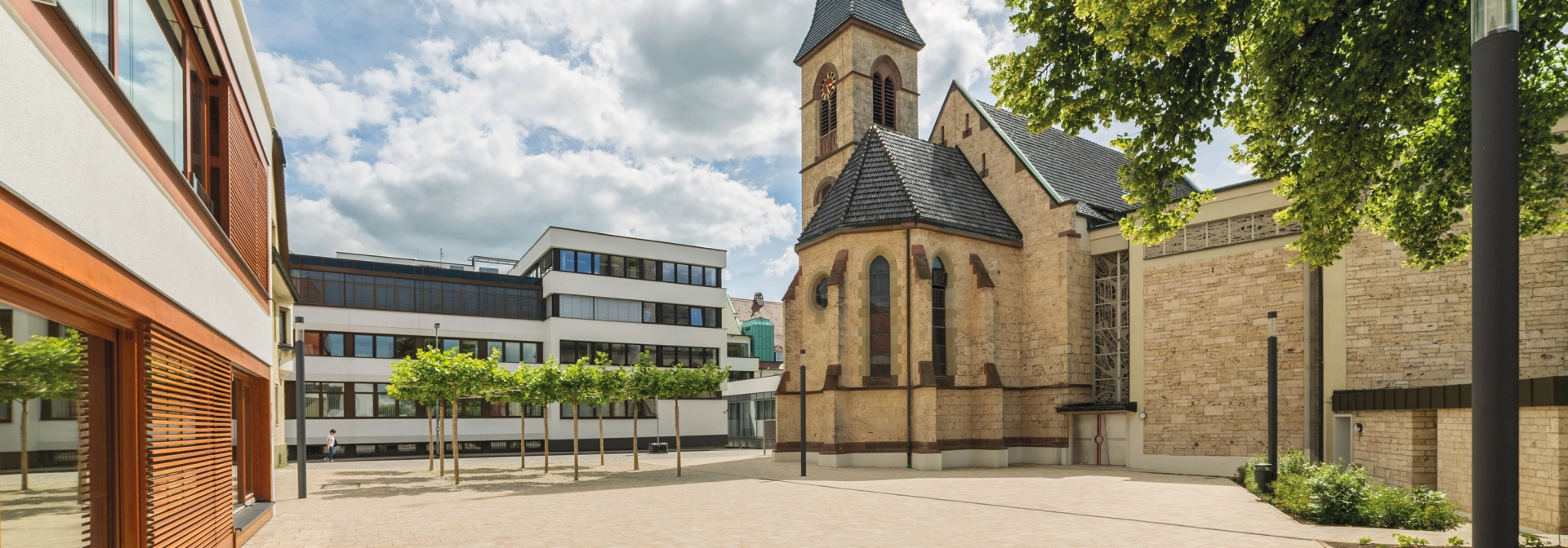Paved church forecourt with modern buildings and historic church