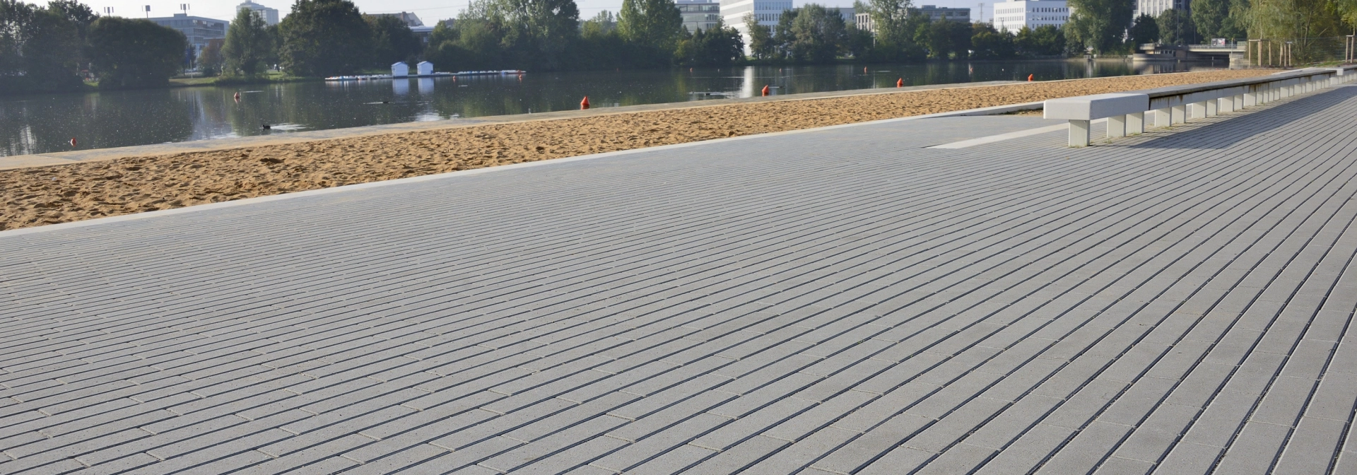 Uferpromenade mit grauen Pflastersteinen im Riegelformat in Reihe verlegt am Ufer des Whörder Sees in Nürnberg.