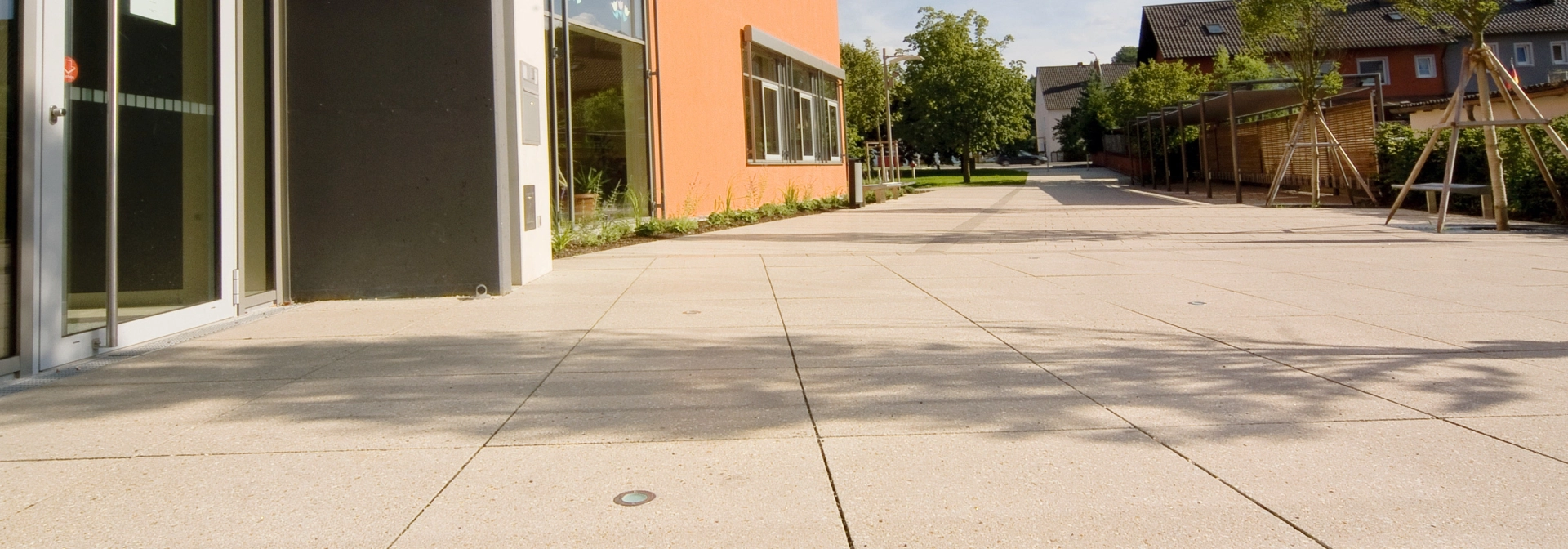Mit großformatigen Platten ausgelegter Vorplatz vor Eingangsbereich zu Schulgebäude