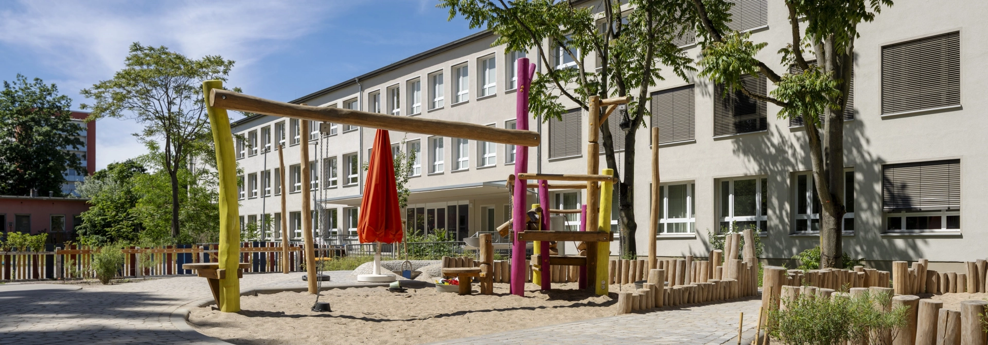 Außenbereich der Kita Wolkenschaf in Berlin mit naturnahen Spielgeräten und versickerungsfähigem GDM.BOLERO.