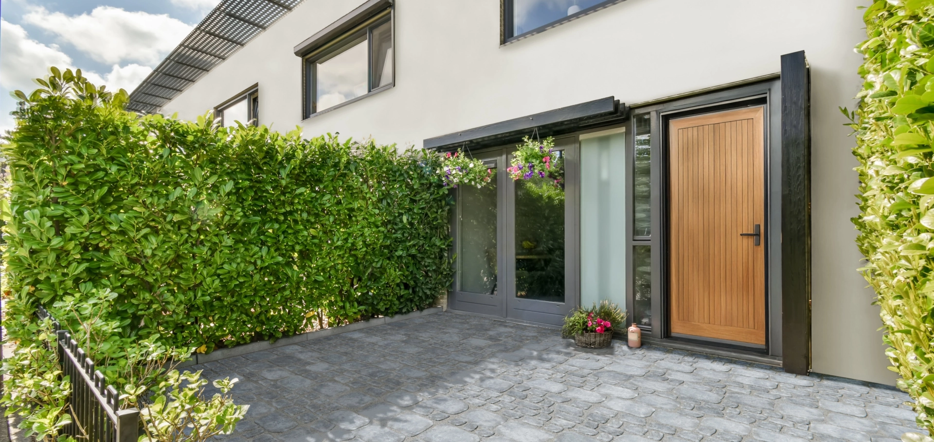 A paved house entrance framed with greenery.