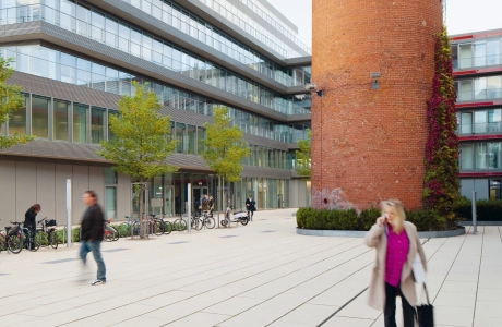 Großer Ziegelturm auf großflächigem Innenhof eines gläsernen Gebäudekomplexes