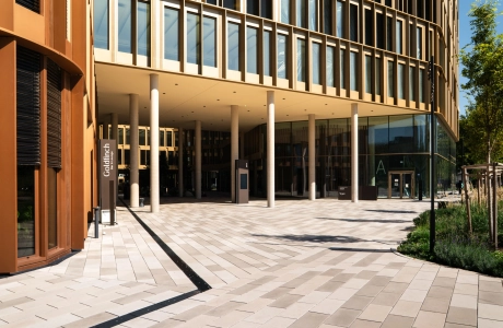 Großes Bürogebäude mit Fensterfassade. Auf dem Vorplatz ist kalksteinfarbener GDM.SCENIC individual verlegt. Am rechten Rand ist ein begrüntes Beet.