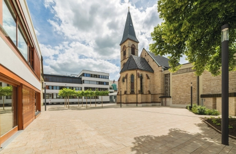 Paved church forecourt with modern buildings and historic church