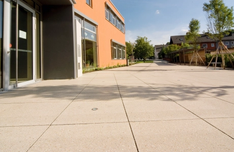 Mit großformatigen Platten ausgelegter Vorplatz vor Eingangsbereich zu Schulgebäude