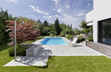 Landscaped garden with pool and large-format patio slabs on a private property.