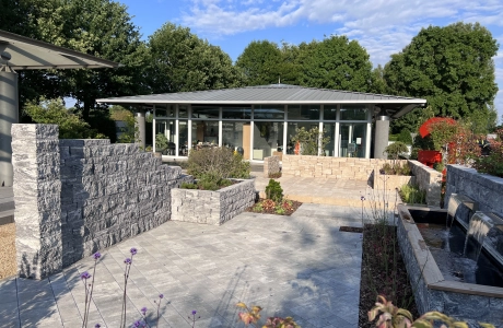 modernes Bürogebäude mit Glasfassade, im Vordergrund ist der Ideen-Garten in Heinsberg zu sehen mit unterschiedlichen Mauern und Pflaster-Flächen