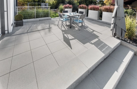 Large terrace with gray patio slabs and steps surrounded by planters.