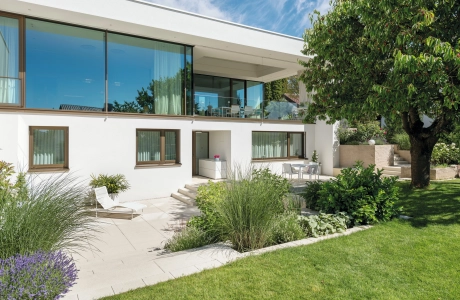 Private modern garden with sandstone-colored terrace and lots of greenery
