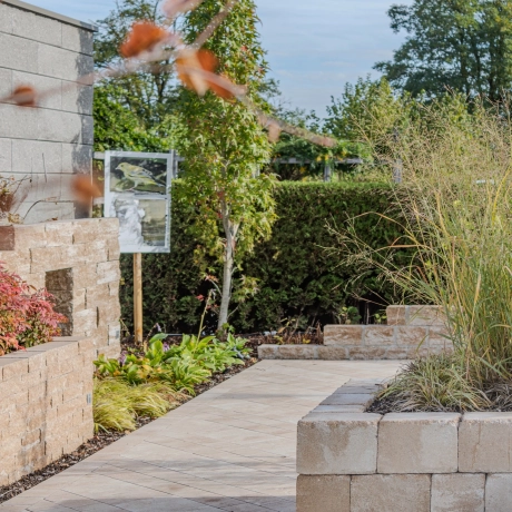 Green and modern garden with walls, patio slabs, steps and paving stones.
