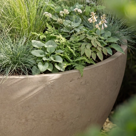 Close-up of a sand-colored plant trough from a formwork-smooth surface made of high-performance concrete with air voids.