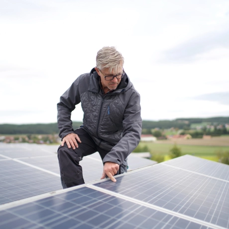 PV systems on the roofs of the production halls. A person is inspecting the surface of the photovoltaic systems.