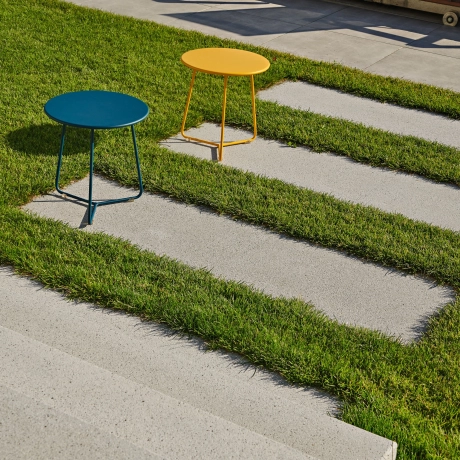 Garten mit Trittplatten und einem gelb und blauen Hocker