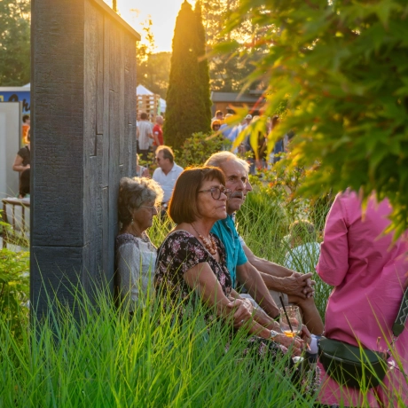 Paar sitzt auf Betonbank im GODELMANN Ideen-Garten und hört der Musik der BigBand der Bundeswehr zu