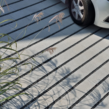 Paved driveway with lawn liner and a car.