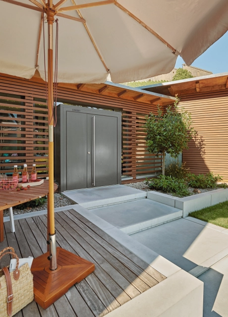 Treppenaufgang aus großformatigen Blockstufen zu Terrasse mit Holzplatten und Sonnenschirm