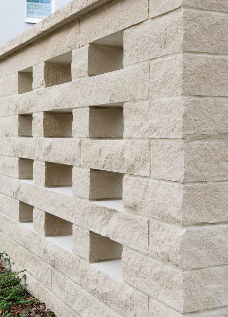 helle beige Mauersteine einer menschenhohen Mauer mit fensterähnlichen Aussparungen