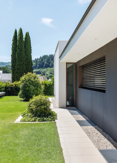 Private modern garden with sandstone-colored terrace and lots of greenery