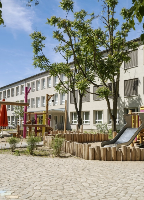 Außenbereich der Kita Wolkenschaf in Berlin mit naturnahen Spielgeräten, Rutsche und versickerungsfähigem GDM.BOLERO.