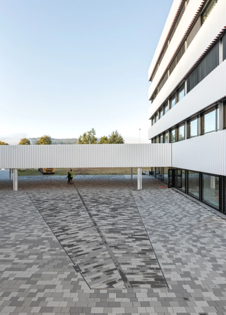 Innenhof vor modernem Sportzentrum mit Pflasterung in unterschiedlichen Grautönen