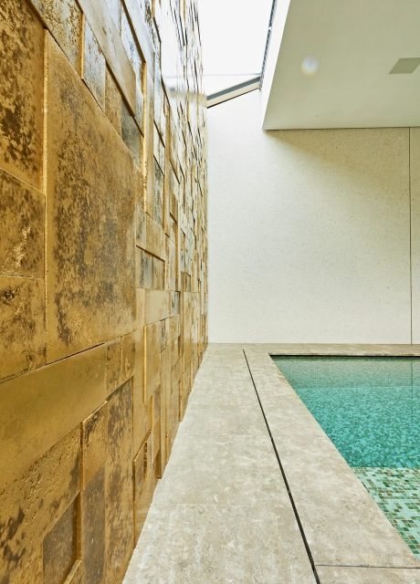 Wand aus gold- und bronzefarbenen Fliesen unterschiedlicher Dicke