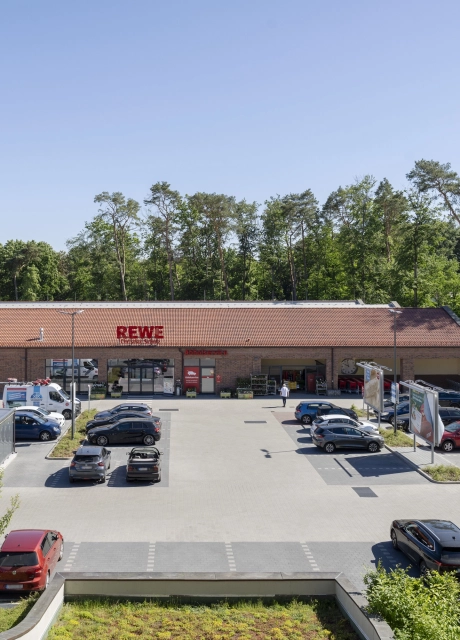 Parkplatz aus GDM.KLIMASTEIN aBG vor dem REWE Markt Christian Schulz mit Stellplätzen, Fahrgassen und Baumstandorten.