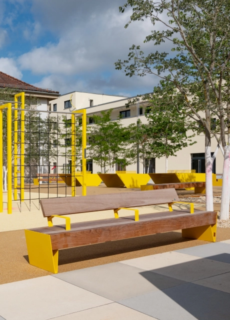 GDM.SCENIC individual auf einer großzügigen Platzfläche mit gelben Sitzbänken, Kletterelementen und jungen Bäumen.