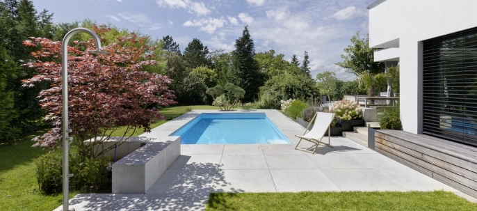 Landscaped garden with pool and large-format patio slabs on a private property.