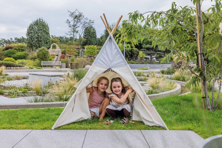 Two girls look out of a white teepee