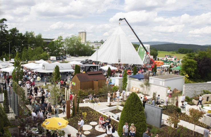 Eine Luftaufnahme zeigt das weitläufige Gelände des „Tag des Gartens“ mit zahlreichen weißen Zelten, Ausstellungsständen und einer großen Besucherzahl, umgeben von grüner Landschaft.