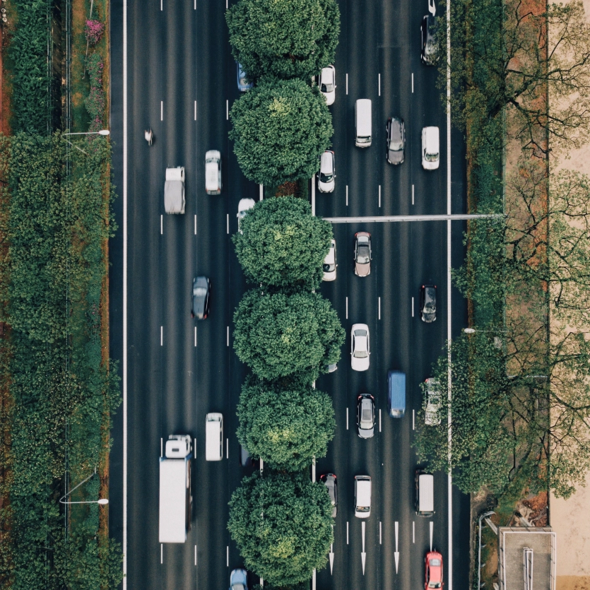 Draufsicht einer vielbefahrenden Verkehrsstraße eingesäumt mit Bäumen