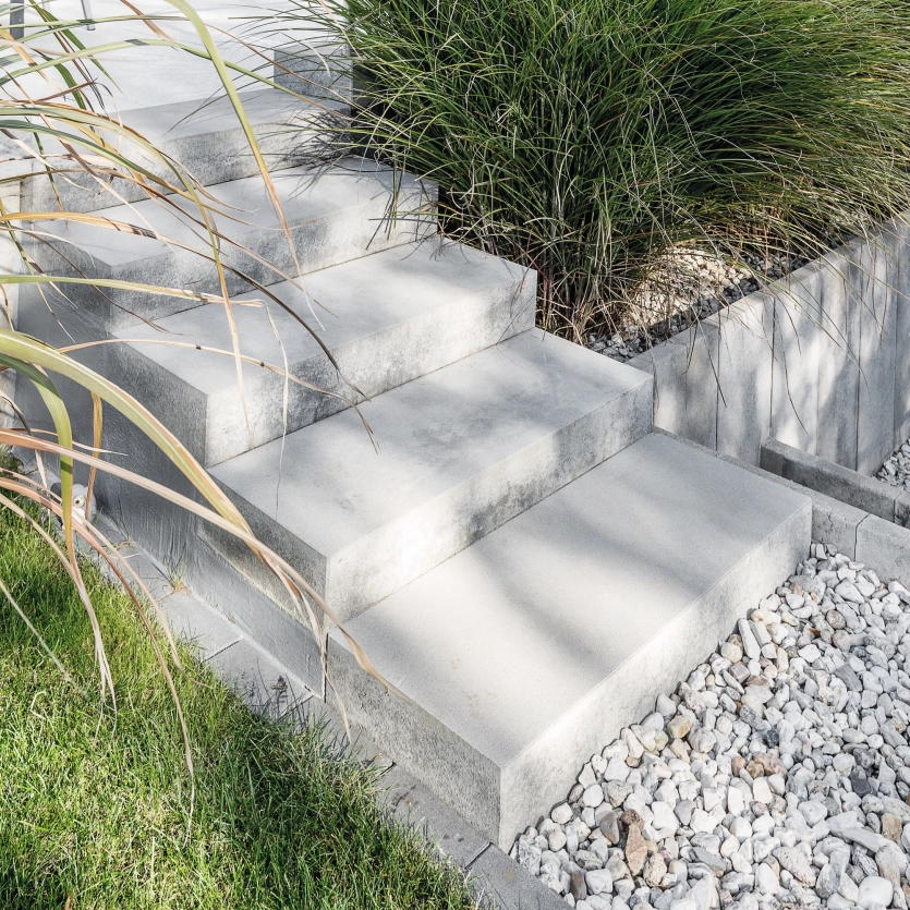 Gray steps in a private garden lead to a pebble path.